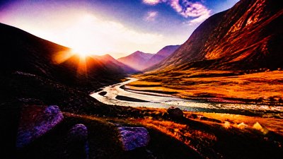 a vast valley with a river winding toward distant mountains at sunrise, no people, no text