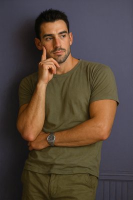 a man leaning against a wall with his hand on his chin