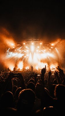 a live music scene with a glowing stage and silhouetted crowd, energetic vertical composition with open space at the top, no text