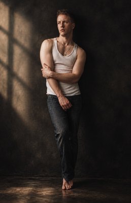 a man standing in a dark room with his arms crossed