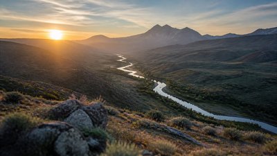 a vast valley with a river winding toward distant mountains at sunrise, no people, no text