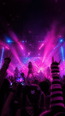 a live music scene with a glowing stage and silhouetted crowd, energetic vertical composition with open space at the top, no text