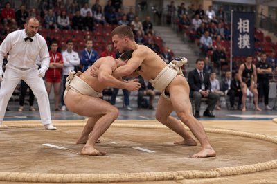 two sumo wrestlers in a ring with spectators watching