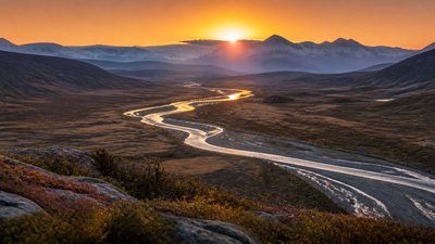 a vast valley with a river winding toward distant mountains at sunrise, no people, no text