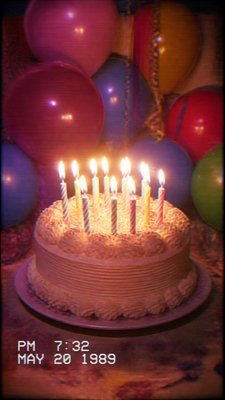 a birthday cake with lit candles surrounded by balloons and confetti, festive vertical composition, no text