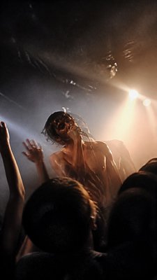 a live music scene with a glowing stage and silhouetted crowd, energetic vertical composition with open space at the top, no text