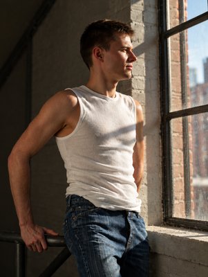 a man leaning against a window with his hands on his hips