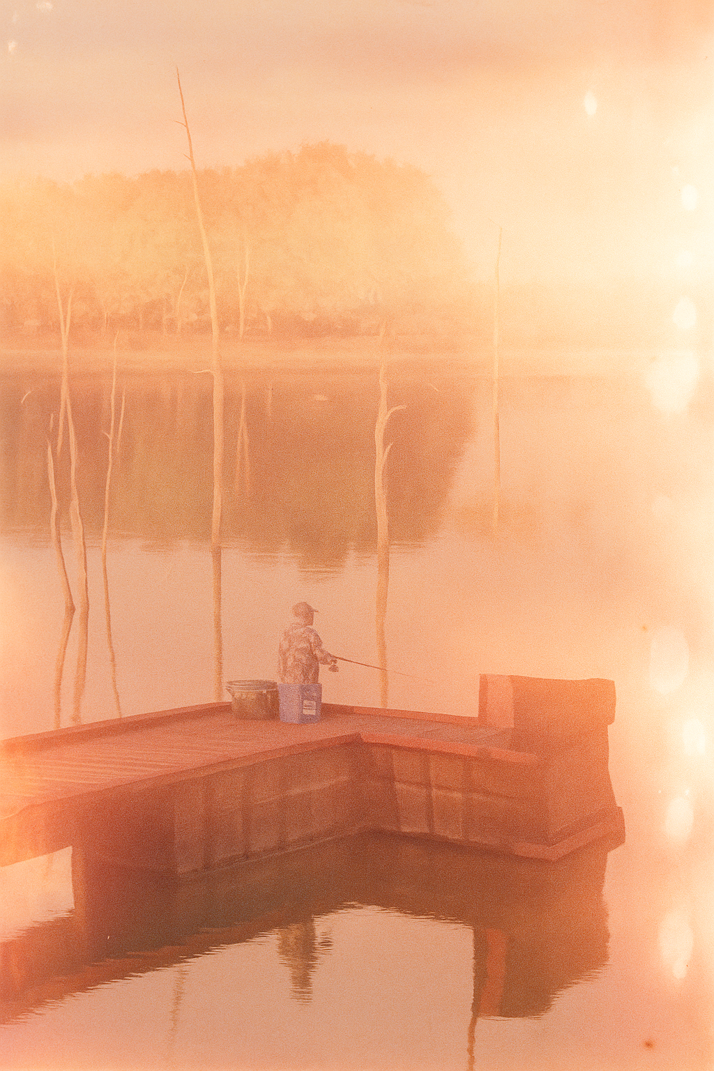 a man sitting on a dock with a fishing rod