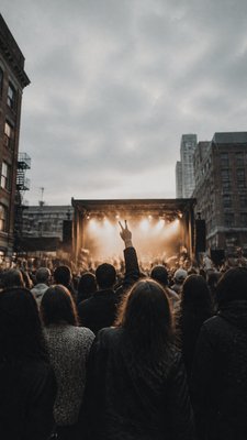 a live music scene with a glowing stage and silhouetted crowd, energetic vertical composition with open space at the top, no text
