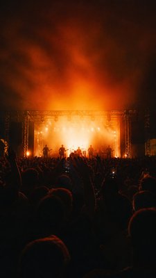 a live music scene with a glowing stage and silhouetted crowd, energetic vertical composition with open space at the top, no text