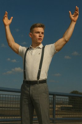 a man in suspenders and a white shirt is holding his hands up