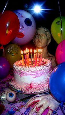 a birthday cake with lit candles surrounded by balloons and confetti, festive vertical composition, no text