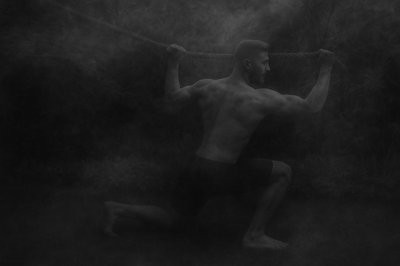 a shirtless man holding a rope in the air