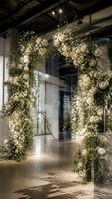 an arch of white roses and eucalyptus in soft morning light, elegant vertical composition with open space, no text