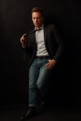 a man in a tuxedo poses for a picture