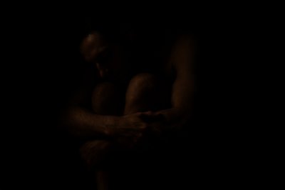 a man sitting in the dark with his arms crossed