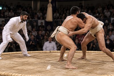 two sumo wrestlers in a ring with a crowd in the background