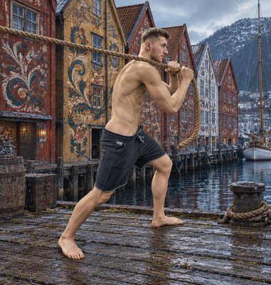 a shirtless man holding a rope while standing on a dock