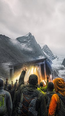 a live music scene with a glowing stage and silhouetted crowd, energetic vertical composition with open space at the top, no text