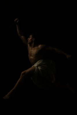 a shirtless man in the dark holding a bat