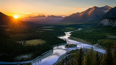 a vast valley with a river winding toward distant mountains at sunrise, no people, no text