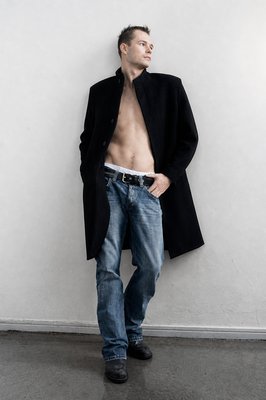 a shirtless man standing against a white wall