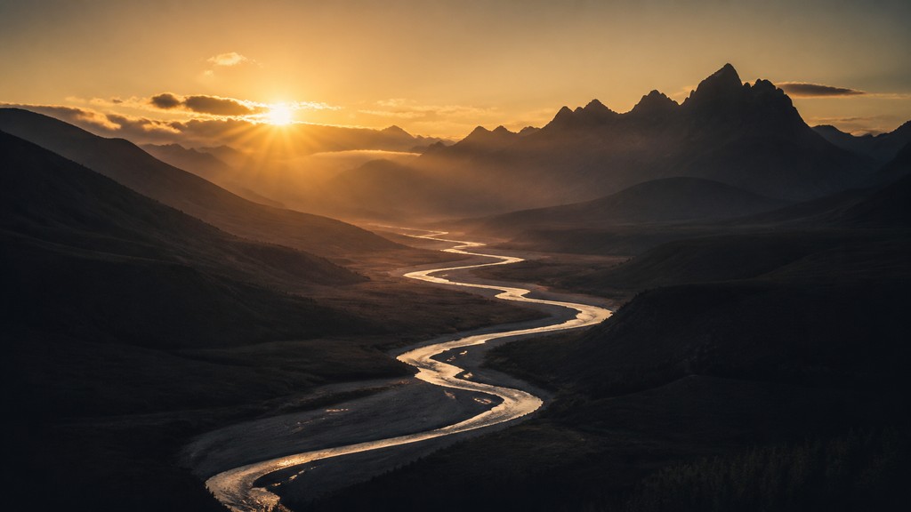a vast valley with a river winding toward distant mountains at sunrise, no people, no text