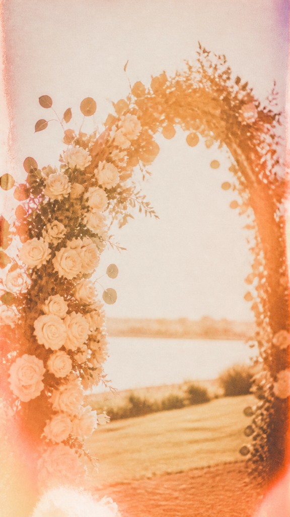 an arch of white roses and eucalyptus in soft morning light, elegant vertical composition with open space, no text