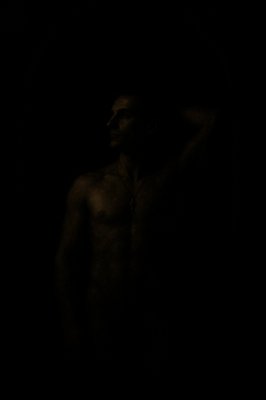 a man standing in the dark with his shirt off