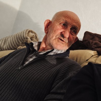 an old man sitting on a couch with his eyes closed