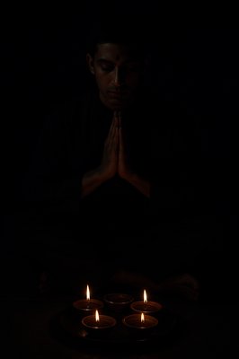 a man sitting in the dark with his hands folded in front of him