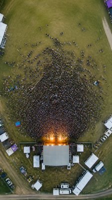 a live music scene with a glowing stage and silhouetted crowd, energetic vertical composition with open space at the top, no text