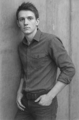 a black and white photo of a man leaning against a wall