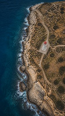a lone lighthouse on a cliff at dusk under a dramatic sky, no text or lettering