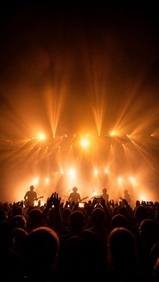 a live music scene with a glowing stage and silhouetted crowd, energetic vertical composition with open space at the top, no text