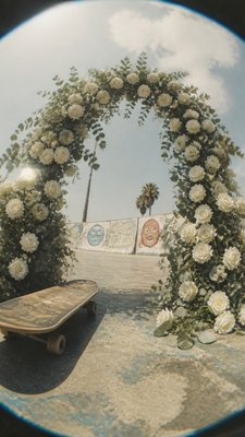 an arch of white roses and eucalyptus in soft morning light, elegant vertical composition with open space, no text