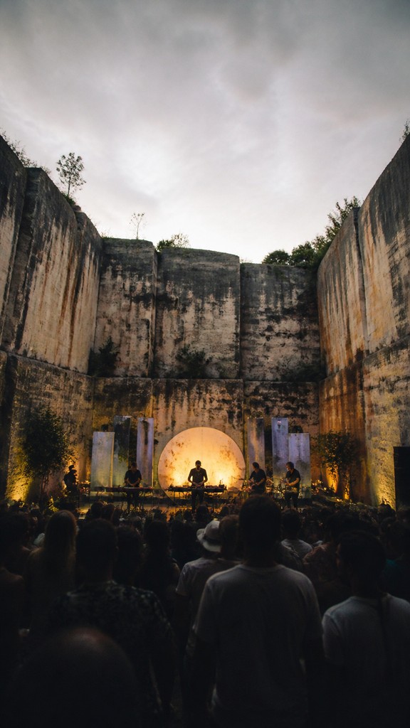 a live music scene with a glowing stage and silhouetted crowd, energetic vertical composition with open space at the top, no text