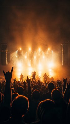 a live music scene with a glowing stage and silhouetted crowd, energetic vertical composition with open space at the top, no text