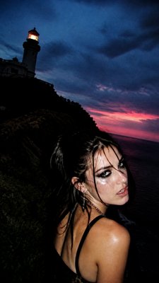 a lone lighthouse on a cliff at dusk under a dramatic sky, no text or lettering