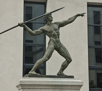 a statue of a man holding a sword in front of a building