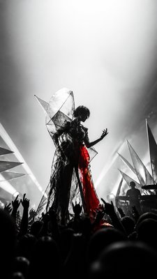 a live music scene with a glowing stage and silhouetted crowd, energetic vertical composition with open space at the top, no text