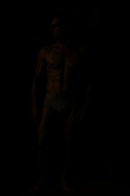 a shirtless man standing in the dark