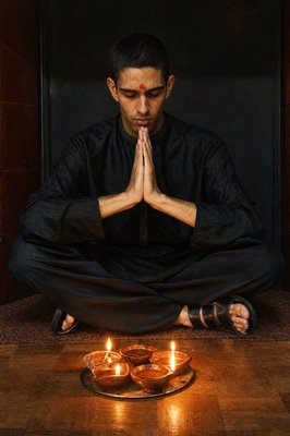 a man sitting on the floor in front of some candles