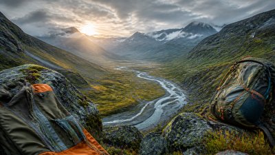 a vast valley with a river winding toward distant mountains at sunrise, no people, no text