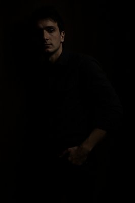 a man standing in the dark with his hands in his pockets