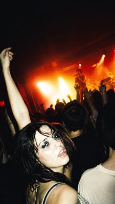 a live music scene with a glowing stage and silhouetted crowd, energetic vertical composition with open space at the top, no text