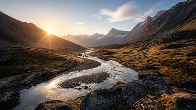 a vast valley with a river winding toward distant mountains at sunrise, no people, no text