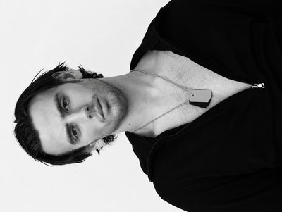 a man with a black shirt and a necklace