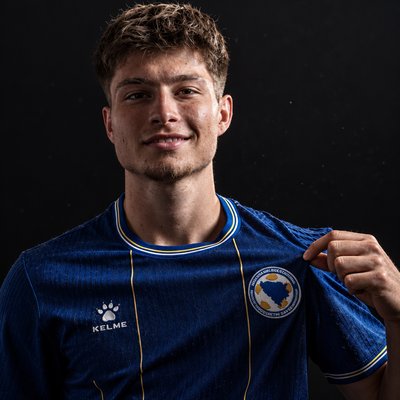 a young man holding a blue soccer jersey