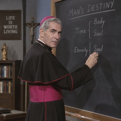 Bishop Fulton Sheen writing on a black board for Life Is Worth Living TV program